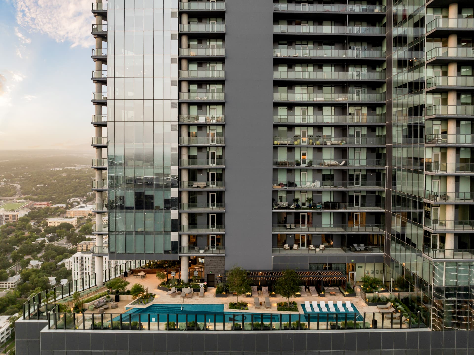 The tower facade at Residences at 6G above the rooftop pool deck at sunset