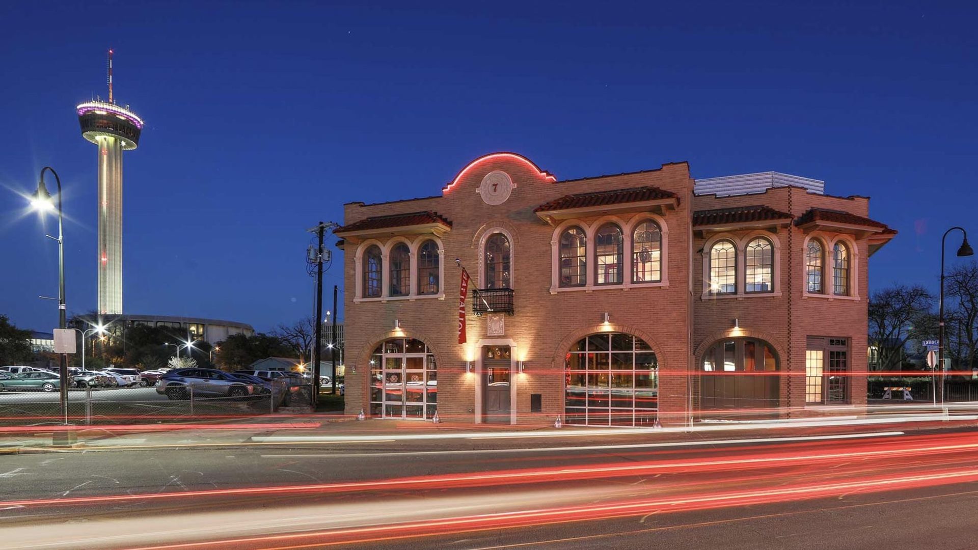 The historic firehouse at dusk, the Battalion neon lit above the bay doors