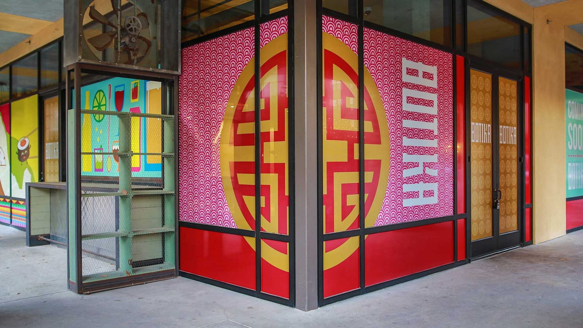 The Botika storefront at Pearl, the red and gold window graphics wrapping the corner