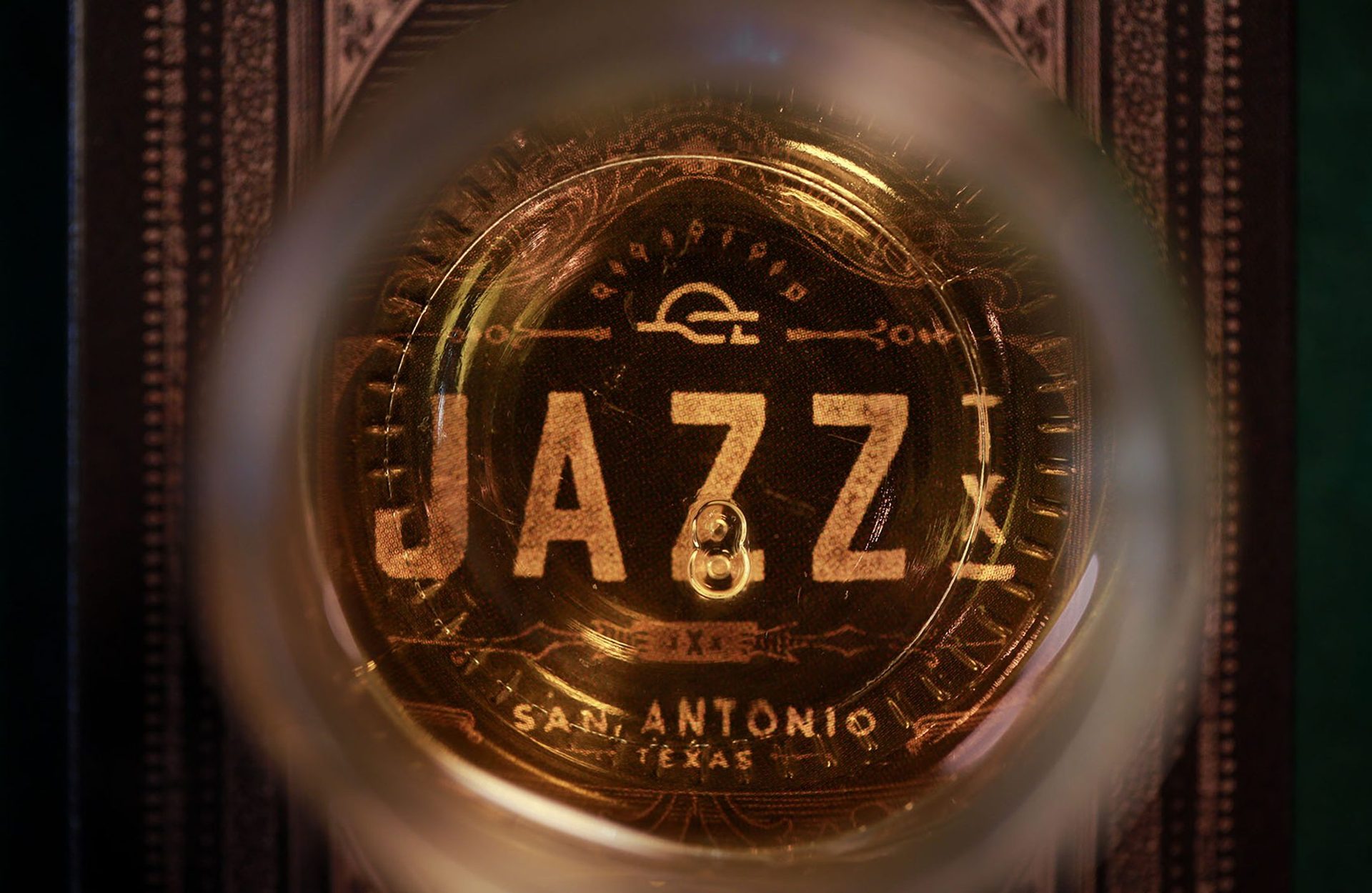 The JAZZ TX seal in gold, read through a glass