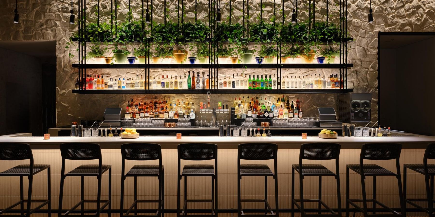 The bar at Kimpton Santo, bottle shelving above the counter against the historic stone wall
