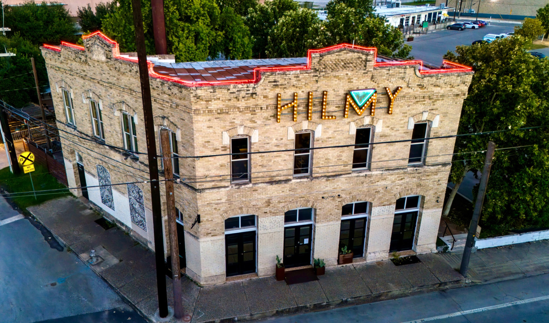 El edificio de HILMY en 430 Austin St, San Antonio, con el letrero iluminado al atardecer.